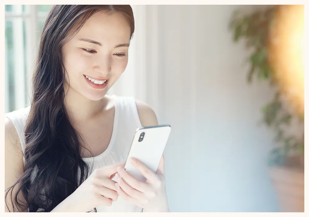 スマートフォンを見ながら予約する女性